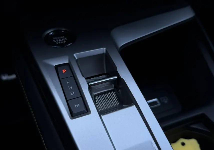 Gros plan sur la console centrale grise avec levier de vitesses automatique et bouton start/stop du Peugeot 408 Hybrid 145 GT.
