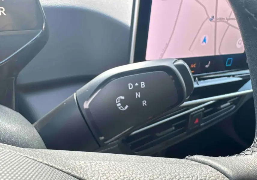 Gros plan sur le levier de vitesses manuel noir du Volkswagen ID.3 2025, avec écran tactile et tableau de bord partiellement visibles.