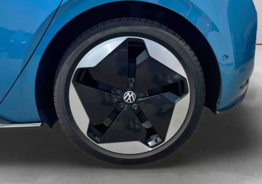 Gros plan sur la roue avant droite bleu métallisé d'une Volkswagen ID.3 avec jante alliage bicolore noire et argent.