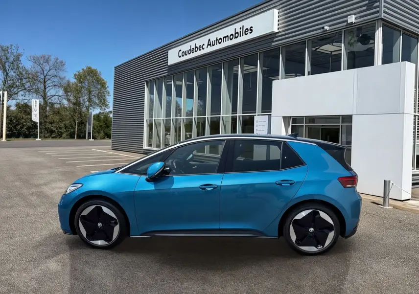 Vue de profil côté gauche d'une Volkswagen ID.3 204 ch Pro S 77 kWh bleu métallisé avec jantes 20 pouces devant un concessionnaire.