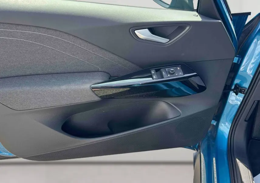 Vue rapprochée de la porte avant gauche bleu métallisé du Volkswagen ID.3 avec commandes électriques et garniture tissu grise.