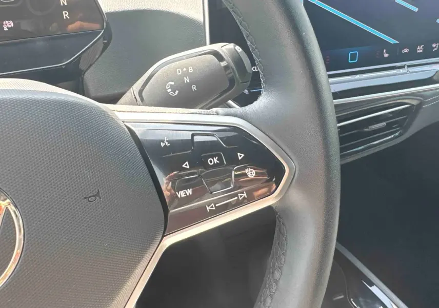 Gros plan sur le volant multifonction noir du Volkswagen ID.3 2025 avec commandes tactiles et écran tactile central visible.