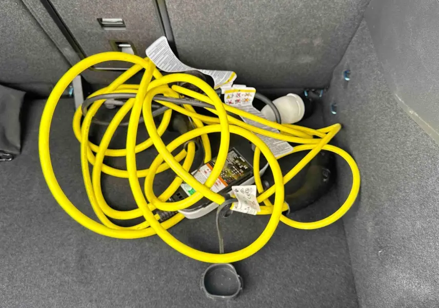 Câble de recharge électrique jaune enroulé dans le coffre d’un Volkswagen ID.3 2025 bleu.