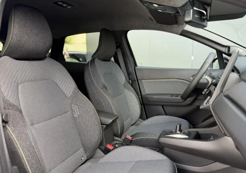 Vue intérieure côté droit du Renault Captur 2026, montrant les sièges tissu gris avec coutures contrastées et console centrale.