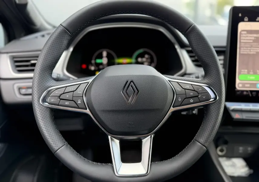 Vue rapprochée du volant noir perforé du Renault Captur 2026 avec commandes intégrées et tableau de bord numérique flou.