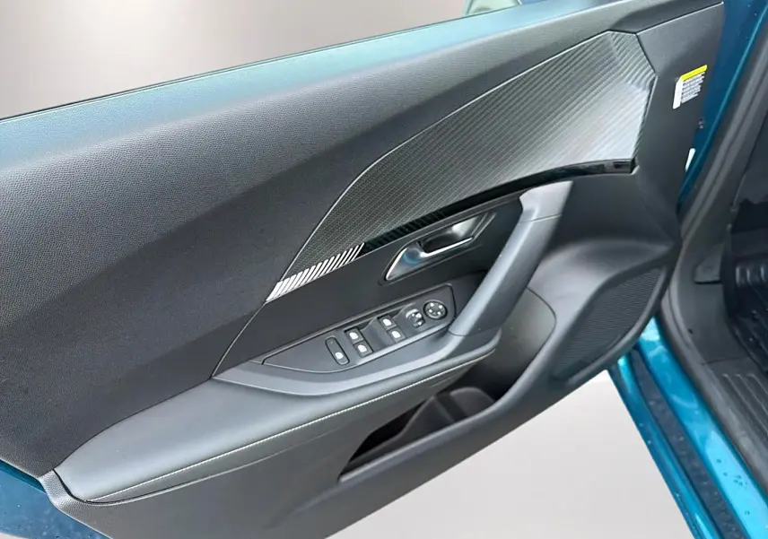 Vue intérieure côté gauche de la porte avant bleu obsession d’un Peugeot 2008 avec commandes de vitres et habillage noir texturé.