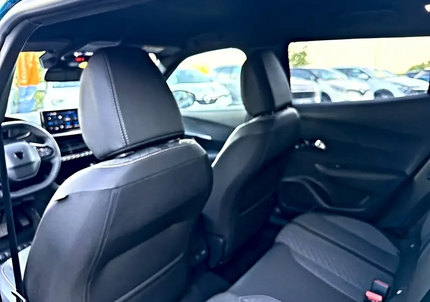 Vue intérieure arrière de la Peugeot 2008 bleu obsession, montrant les sièges avant et arrière en tissu noir embossé.