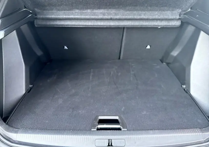 Coffre ouvert du Peugeot 2008 bleu obsession, vue arrière montrant l'espace de chargement vide et tapis noir.