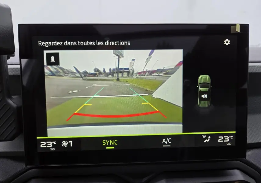Écran tactile intérieur montrant la caméra de recul du Dacia Bigster blanc glacier avec lignes de guidage colorées.