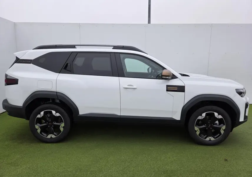 Profil côté gauche du Dacia Bigster blanc glacier avec rétroviseurs brun cuivré et jantes alliage noires.