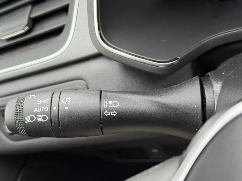 Gros plan sur la commande des feux et clignotants du Renault Captur 2025, intérieur noir, côté gauche du volant.