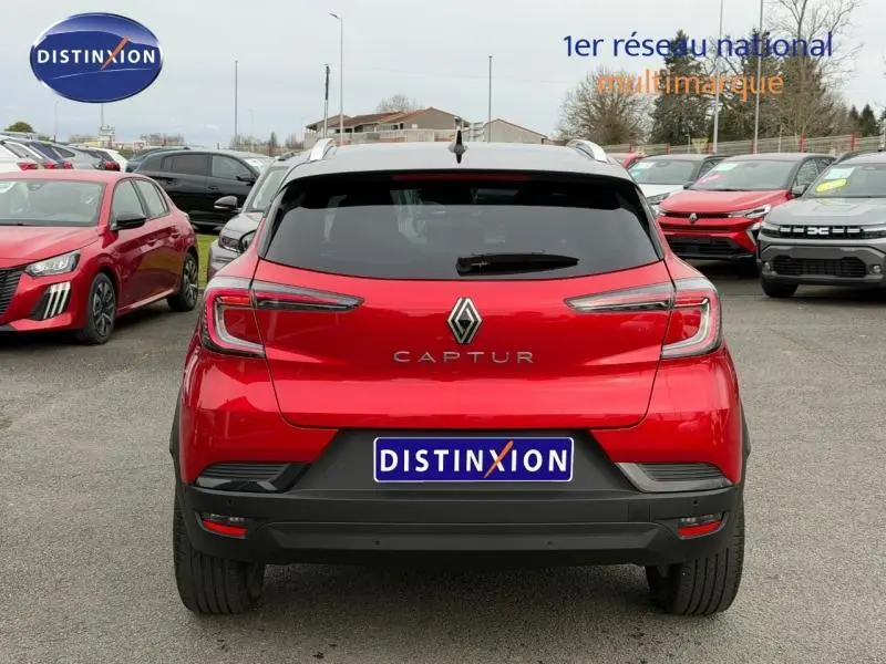 Vue arrière d'un Renault Captur 2025 rouge flamme, version 1.0 Eco-G 100ch Techno, sur un parking extérieur.
