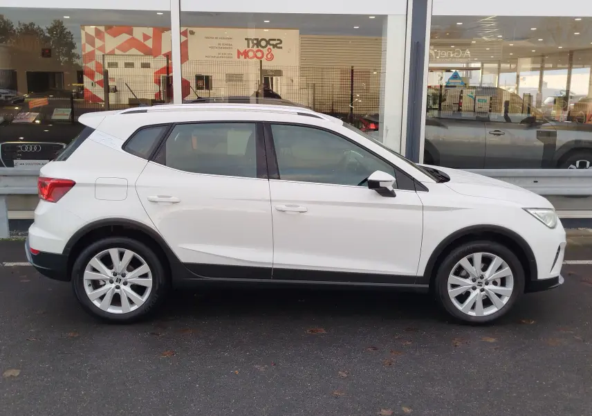 Vue de profil côté gauche d'un SEAT Arona blanc Candy 2023 avec jantes alliage et toit ouvrant panoramique.