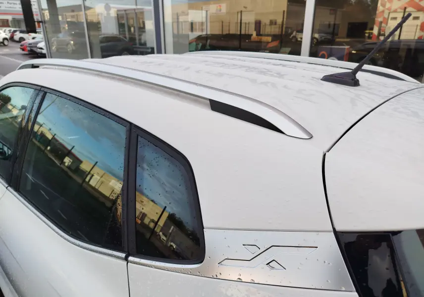 Vue arrière côté gauche du SEAT Arona blanc Candy 2023 avec logo Xperience et barres de toit visibles.