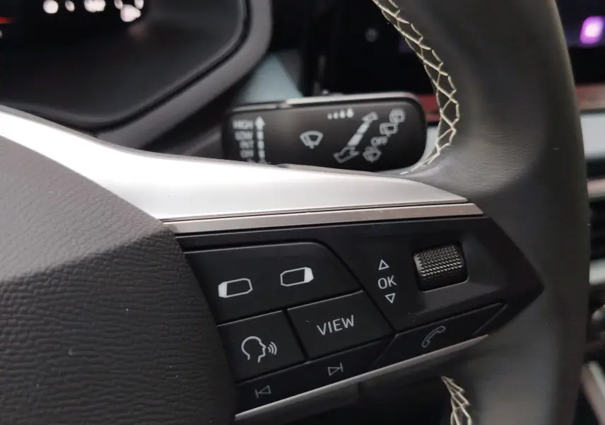 Gros plan sur les commandes au volant côté gauche du SEAT Arona 2023, cuir noir avec surpiqûres blanches.