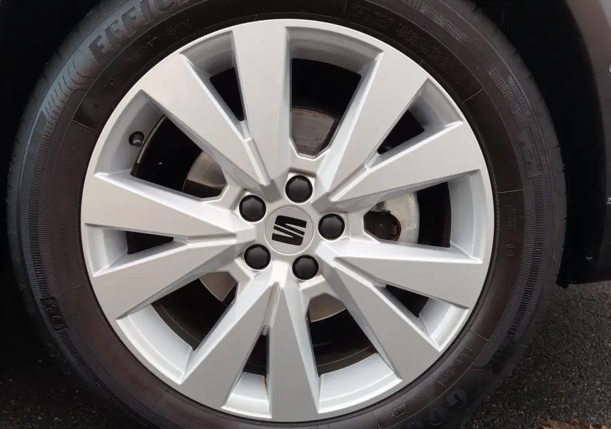 Gros plan sur la jante argentée avec logo SEAT, montée sur un pneu Goodyear, sur un SEAT Arona blanc.