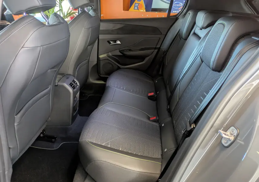 Vue intérieure côté droit des sièges arrière en cuir et tissu gris avec surpiqûres vertes du Peugeot 308 Hybrid 2026.