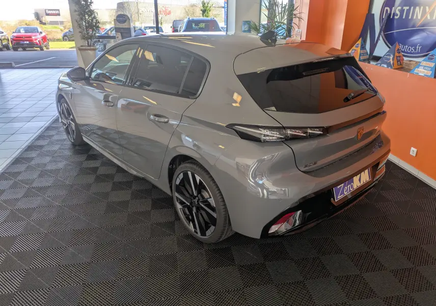 Vue 3/4 arrière droite d’une Peugeot 308 gris selenium hybride 2026 avec jantes noires bicolores et vitres teintées.