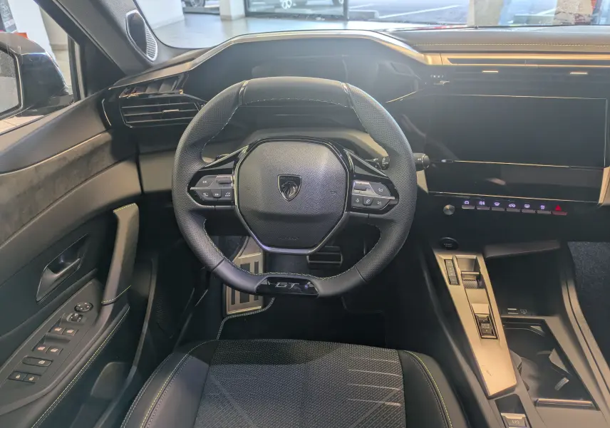 Vue intérieure frontale du poste de conduite du Peugeot 308 gris Selenium, volant GT compact et écran tactile large.