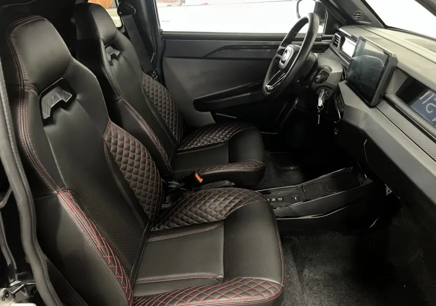 Vue intérieure côté conducteur de la LIGIER JS50 2026 avec sièges noirs surpiqués rouges et tableau de bord moderne.