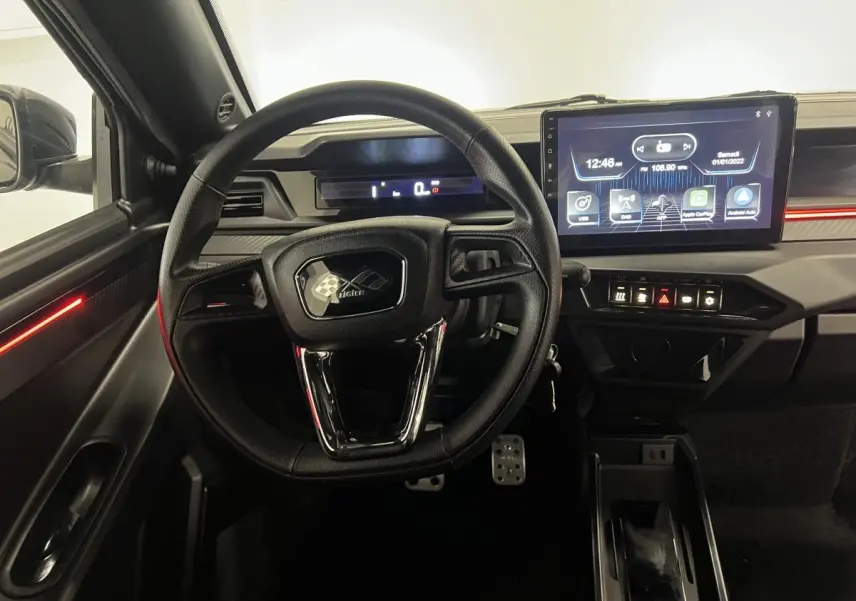 Vue intérieure centrée sur le volant noir et le tableau de bord avec écran tactile du Ligier JS50 Ultimate 2026.