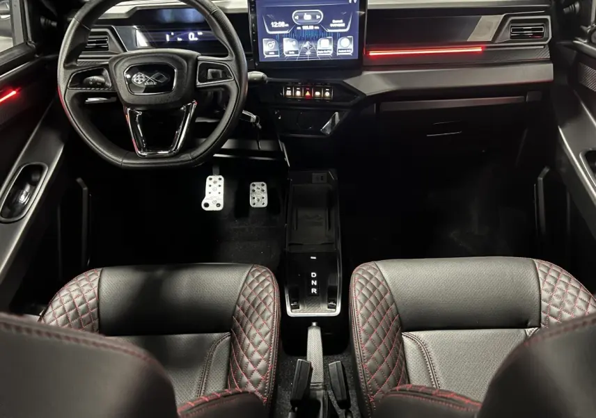 Vue intérieure avant du LIGIER JS50 noir avec sièges Ultimate surpiqués rouges et écran tactile central lumineux.