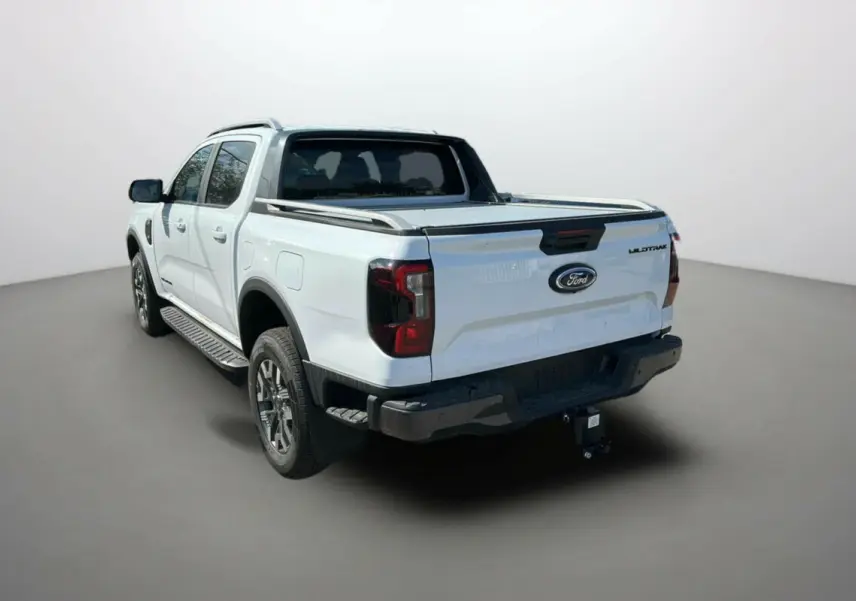 Ford Ranger blanc en 3/4 arrière droit, avec benne couverte et attelage visible.