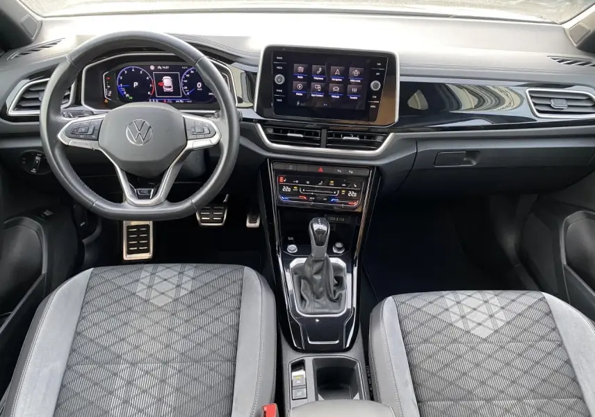 Vue intérieure du tableau de bord et console centrale du Volkswagen T-Roc 2024 avec volant multifonction et écran tactile.