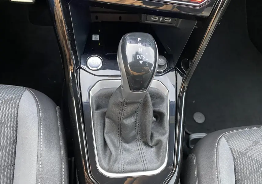 Gros plan sur la console centrale du Volkswagen T-Roc 2024 avec levier de vitesses noir et sellerie grise.