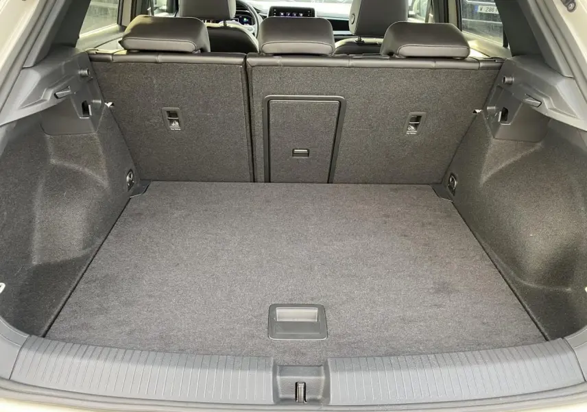 Vue du coffre ouvert du Volkswagen T-Roc gris 2024, montrant l'espace de rangement arrière et les dossiers de sièges rabattus.