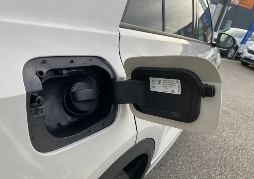 Vue rapprochée de la trappe à carburant ouverte côté gauche d’un Volkswagen T-Roc blanc.