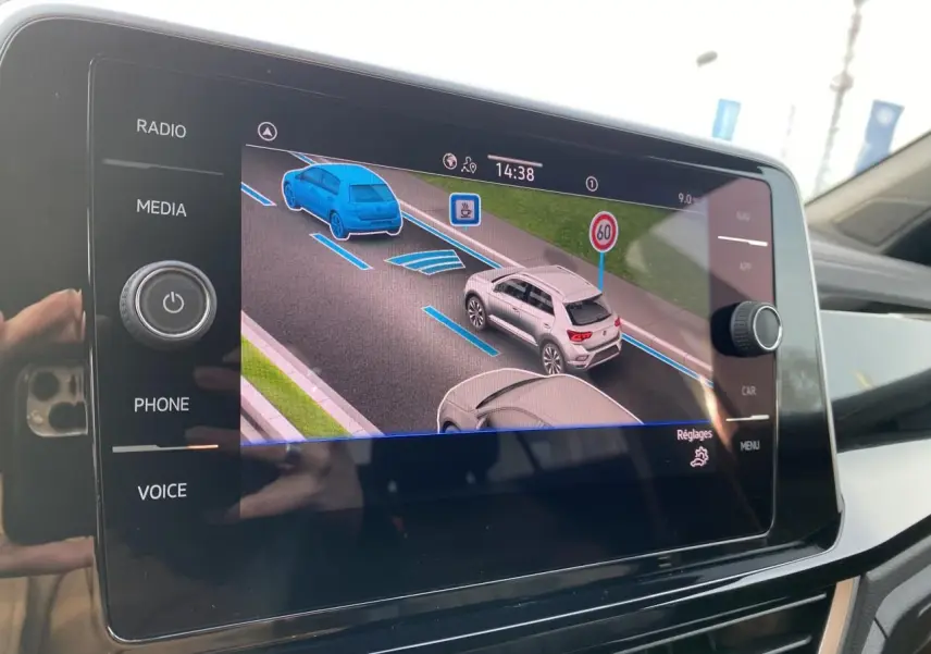Écran tactile intérieur montrant l'assistance au maintien dans la voie avec représentation de véhicules et signalisation routière.