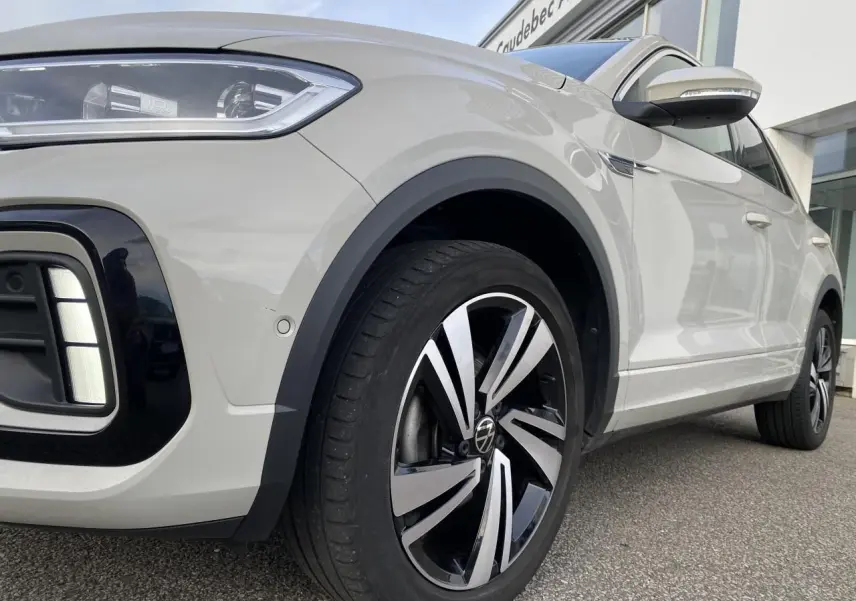 Vue 3/4 avant droit du Volkswagen T-Roc gris avec jante alliage noir et argent et détails de phares LED.