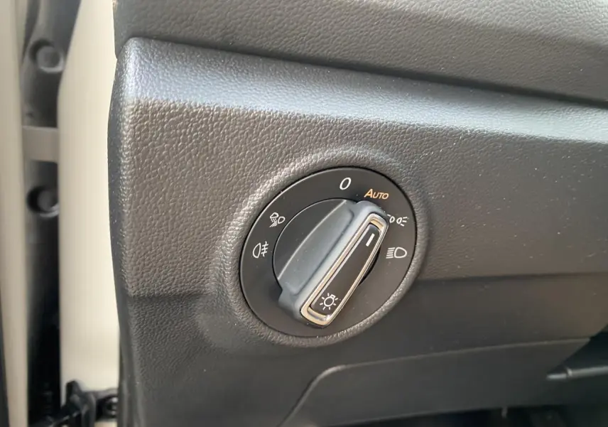 Gros plan sur le bouton de commande des phares dans l’habitacle du Volkswagen T-Roc gris 2024.
