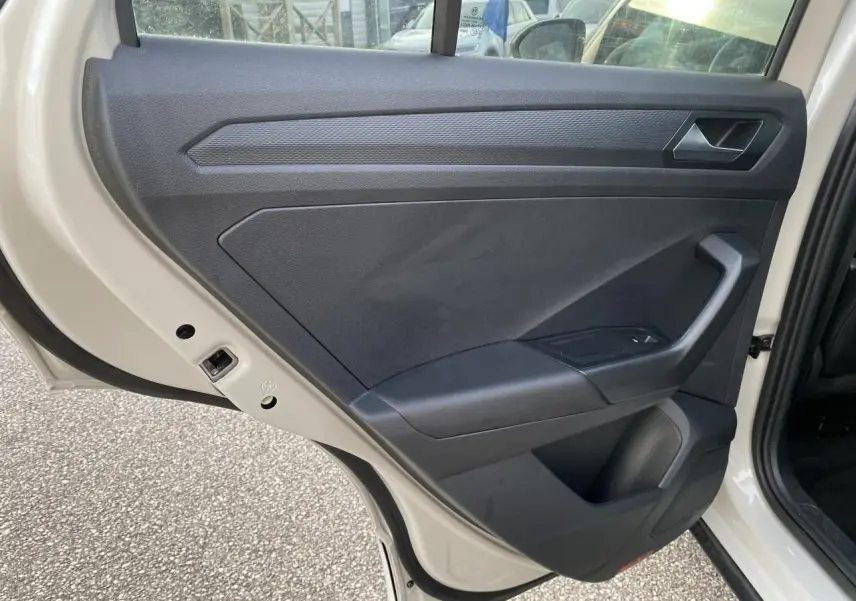 Vue intérieure de la porte arrière gauche grise d'un Volkswagen T-Roc 2024 avec garniture noire et poignée intégrée.