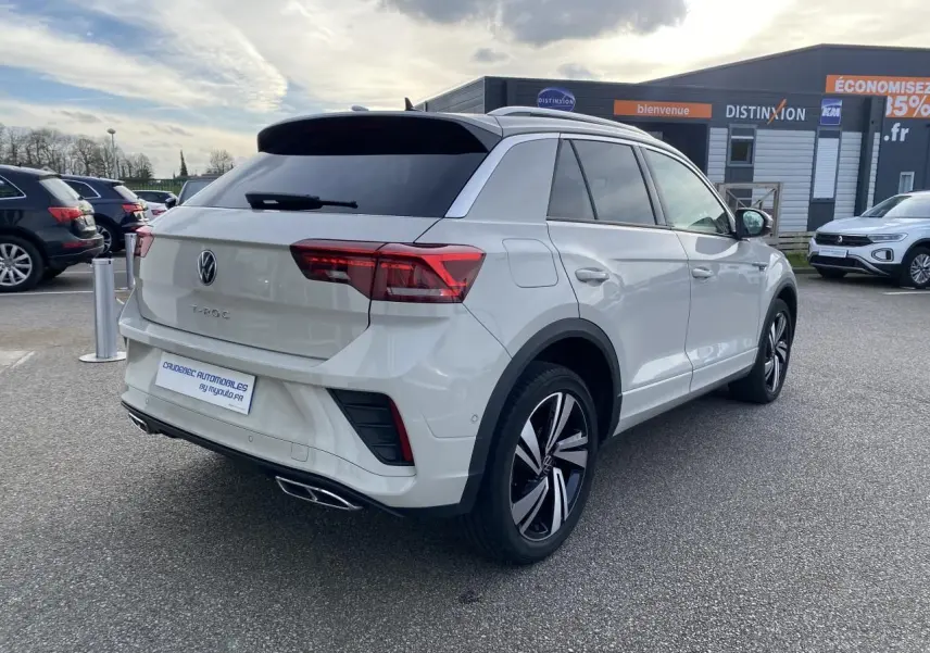 Vue 3/4 arrière droite d'un Volkswagen T-Roc gris clair avec jantes alliage noires et vitres teintées.