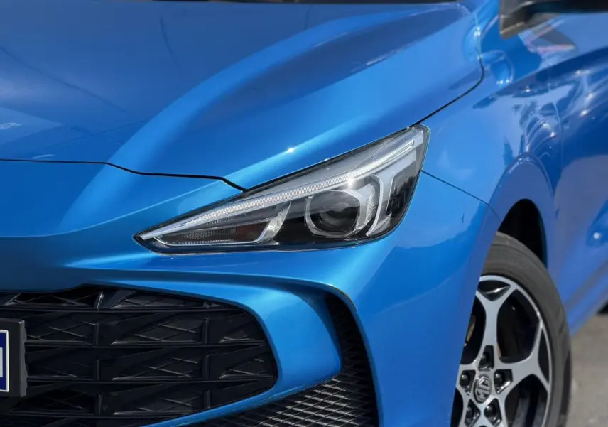 Gros plan sur l'avant droit bleu Como du MG3 1.5 Hybrid+ 195 Comfort, avec phare LED et calandre noire ajourée.