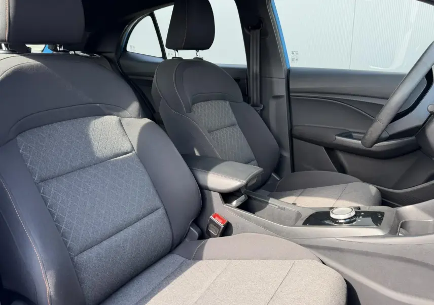 Vue intérieure côté avant droit du MG3 2025, sièges en tissu noir avec accoudoir central et console moderne.
