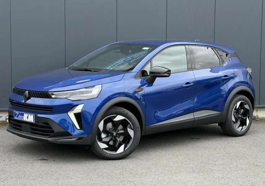 Renault Captur 2026 bleu Iron en 3/4 avant droit, avec jantes noires et détails noirs brillants sur les rétroviseurs.