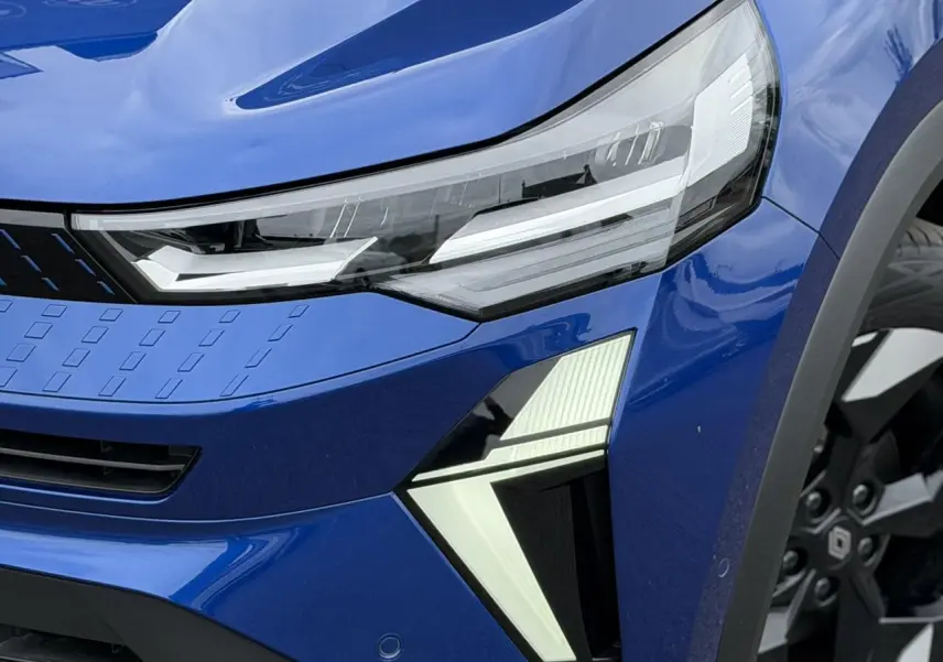 Gros plan sur l'avant droit du Renault Captur Bleu Iron, mettant en valeur le phare LED et la jante aluminium 18 pouces.