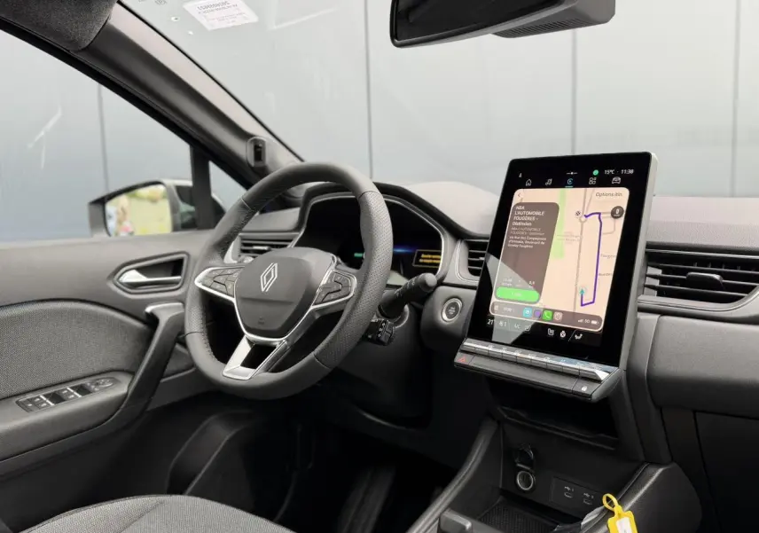 Vue intérieure côté conducteur du Renault Captur 2026, volant multifonction et grand écran tactile central allumé.