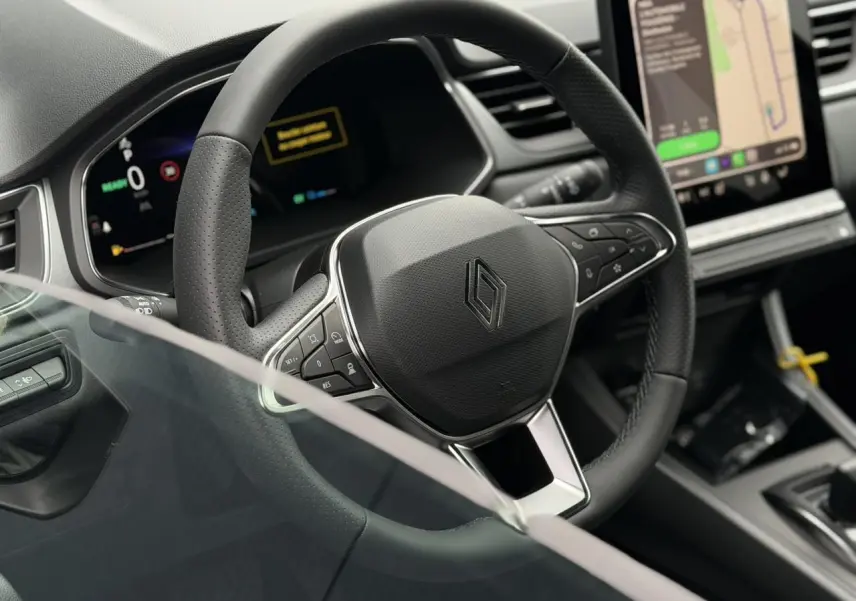 Vue rapprochée du volant noir et du tableau de bord numérique du Renault Captur 2026, avec écran tactile central.
