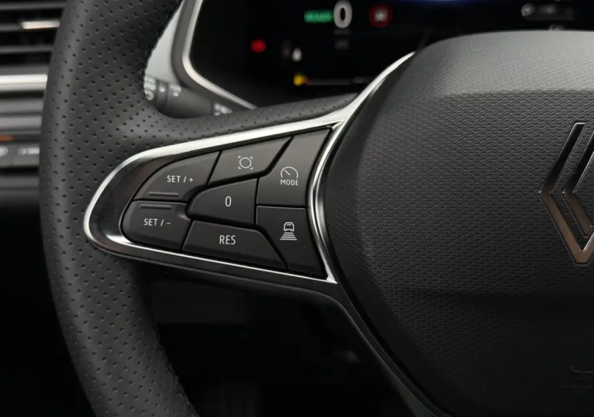Gros plan sur le côté gauche du volant noir perforé du Renault Captur 2026, avec commandes intégrées et logo central.