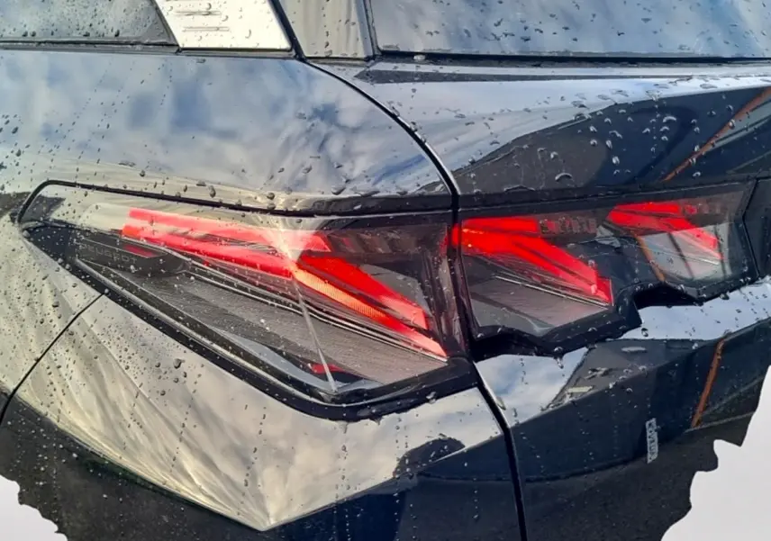 Gros plan sur le feu arrière droit rouge et noir d’un Peugeot 5008 Hybrid 145 GT e-dcs6 noir sous la pluie.