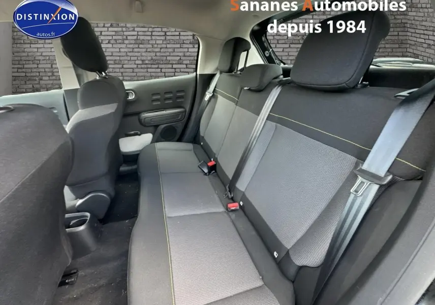 Vue intérieure arrière montrant les sièges arrière en tissu gris et noir avec surpiqûres jaunes d'une Citroën C3 noire 2023.