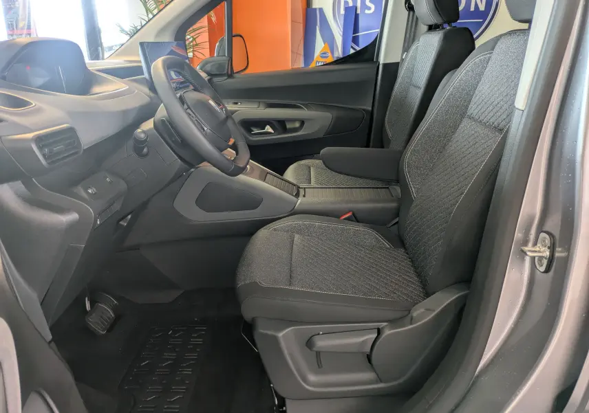 Vue intérieure côté conducteur du Peugeot Rifter gris Artense 2025, montrant les sièges avant et le tableau de bord moderne.