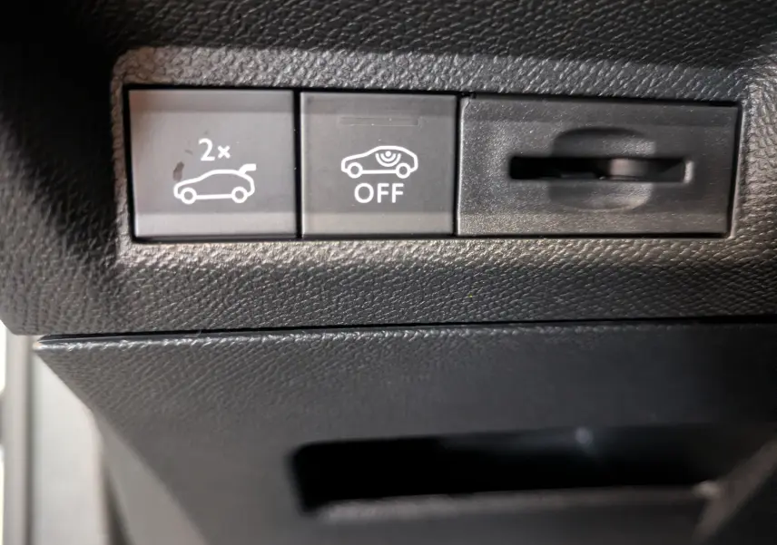 Gros plan sur les boutons de commande intérieurs noirs du Peugeot 3008, avec pictogrammes blancs de coffre et capteurs.