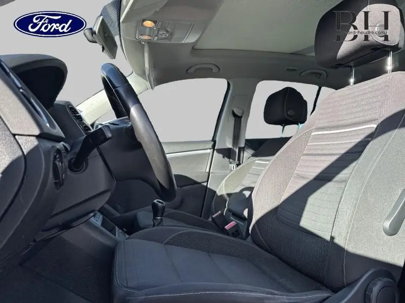 Vue intérieure côté conducteur du Volkswagen Tiguan 2016 avec sièges gris et volant cuir multifonction.