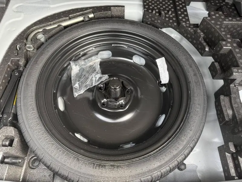 Vue rapprochée de la roue de secours noire dans le coffre d'une CUPRA Formentor blanc Nevada métallisé 2025.