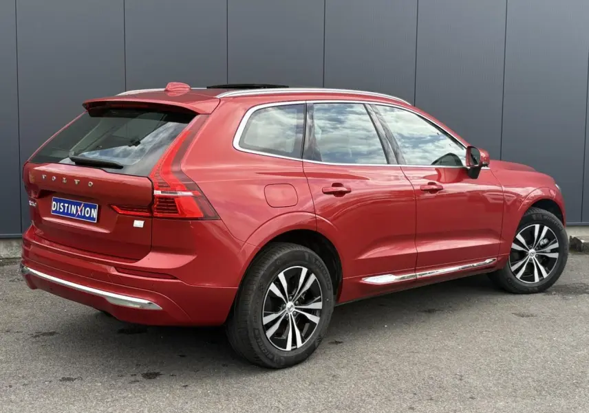 Vue 3/4 arrière droite d'un Volvo XC60 T6 AWD PHEV 2024 rouge Fusion avec jantes alliage et contour chromé.